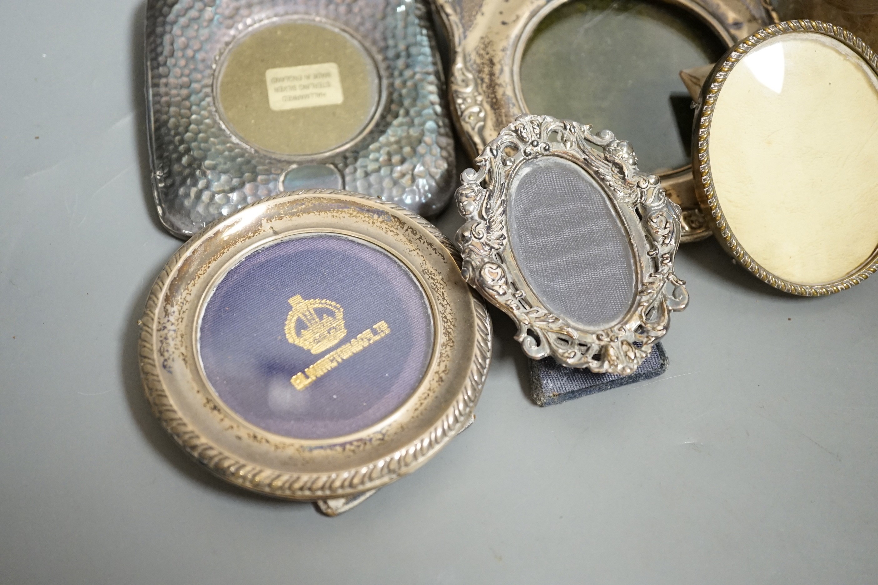 Four small silver mounted photograph frames, one brass frame, a silver lidded jar and one other and a 925 handbag pill box.